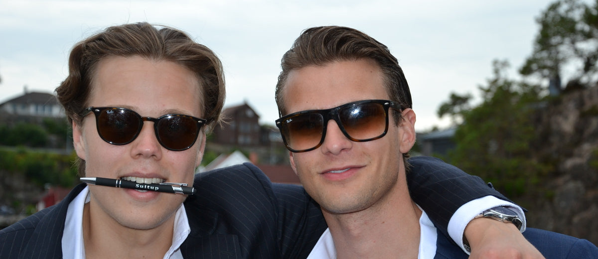 To gutter i SuitUp-dress på SuitUp-festen, den ene med en SuitUp-penn i munnen